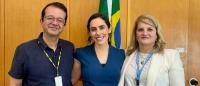 three professional researchers standing in front of flag